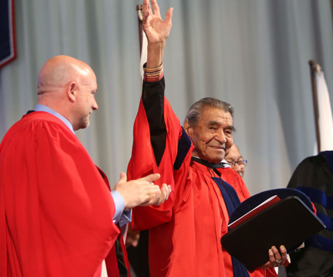 A man raising his hand, wearing red coat