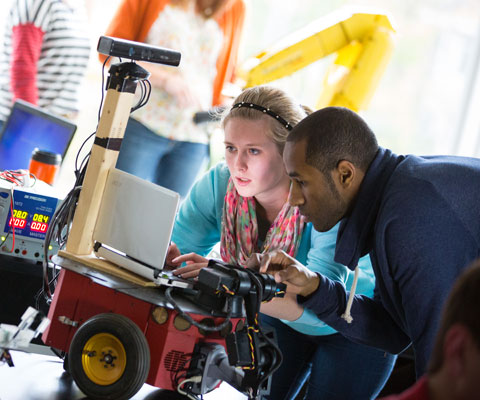 A female student and male student work on a robot.