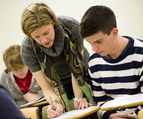 A young female teacher explaining schoolwork to a young male student.