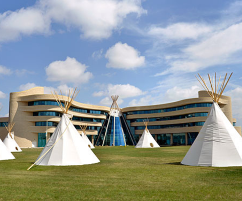 Traditional tipis on the grass in front of the First Nations University Regina campus.