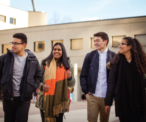 Group of four diverse students walking